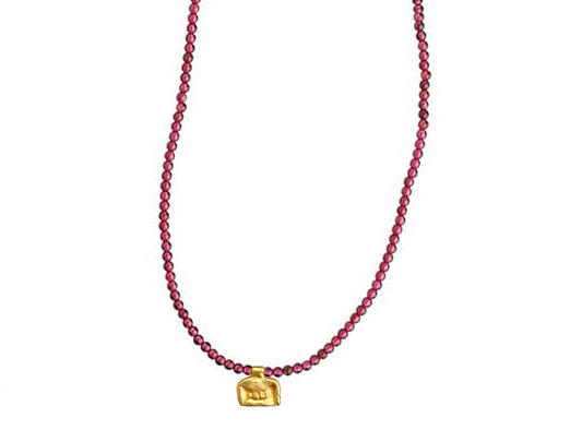 A beaded choker necklace in semiprecious stone featuring a gold amulet cast from an ancient Egyptian artifact. 